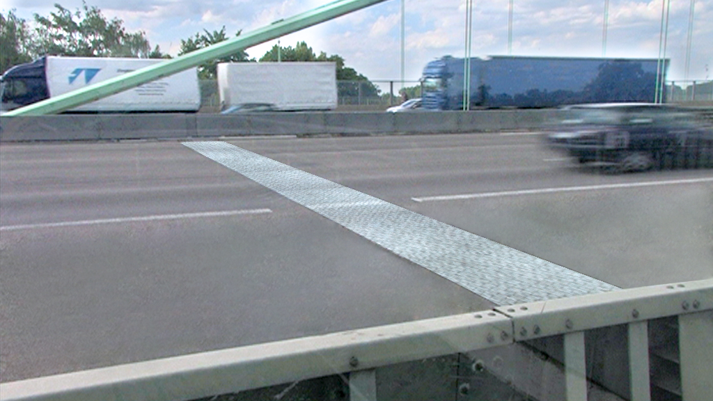 Blick auf eine Autobahn mit einem Metallüberbau und vorbeifahrenden Lkw und Autos.