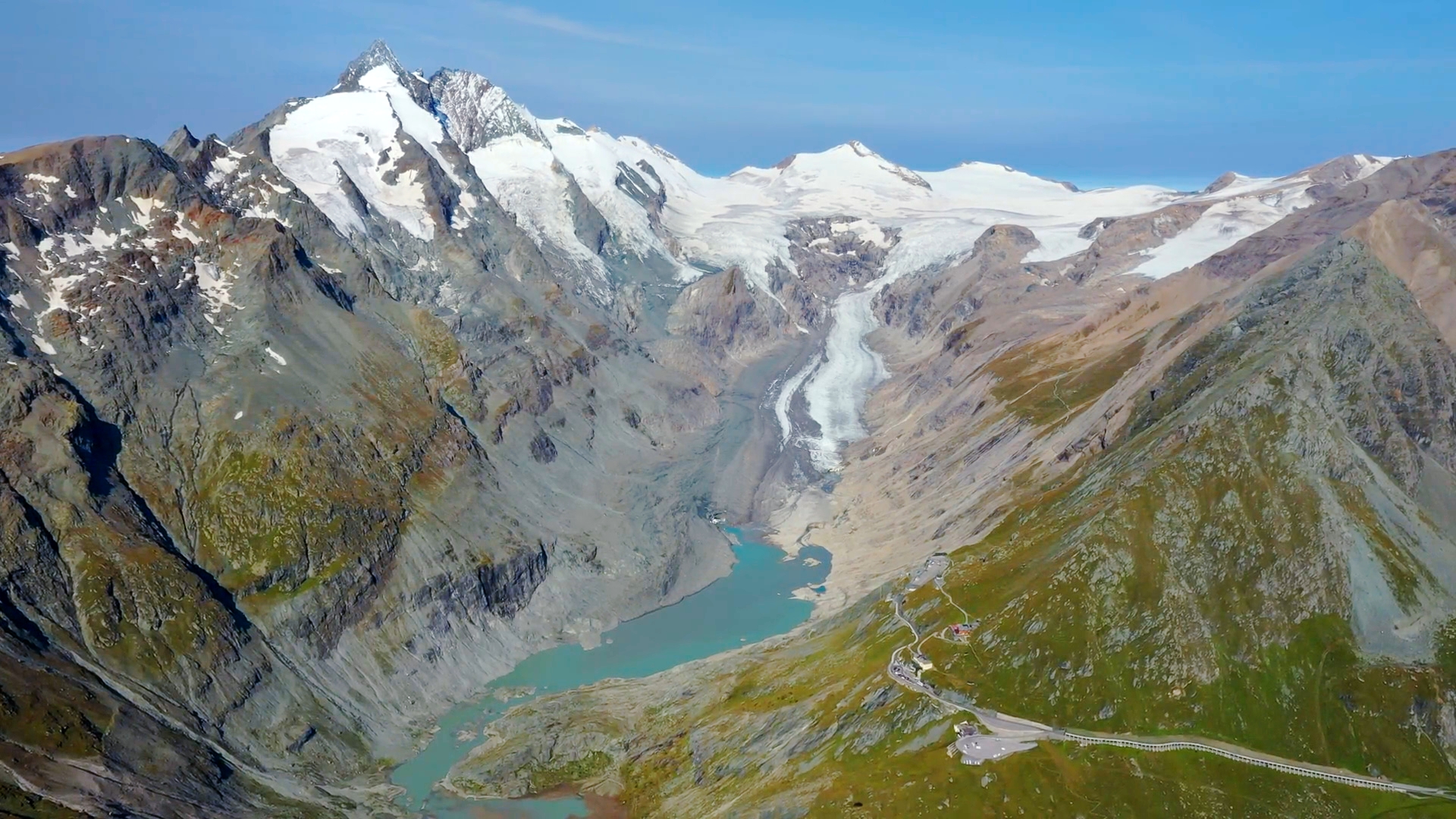 Berglandschaft mit schneebedeckten Gipfeln, Gletscher und einem türkisfarbenen See im Tal