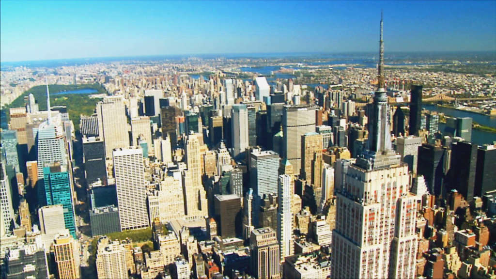 Luftaufnahme von New York City mit dem Empire State Building im Vordergrund und der Skyline im Hintergrund.