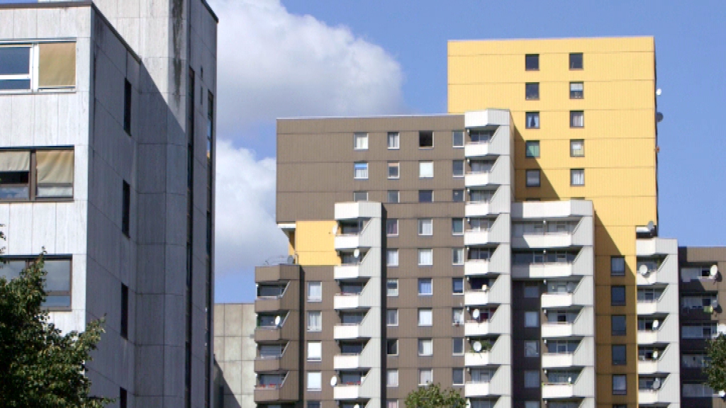 Moderne Wohngebäude mit unterschiedlichen Farben und Balkonen vor blauem Himmel.