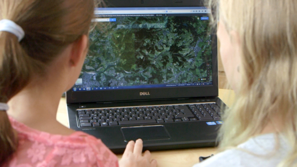 Zwei Mädchen betrachten eine digitale Karte auf einem Laptop.