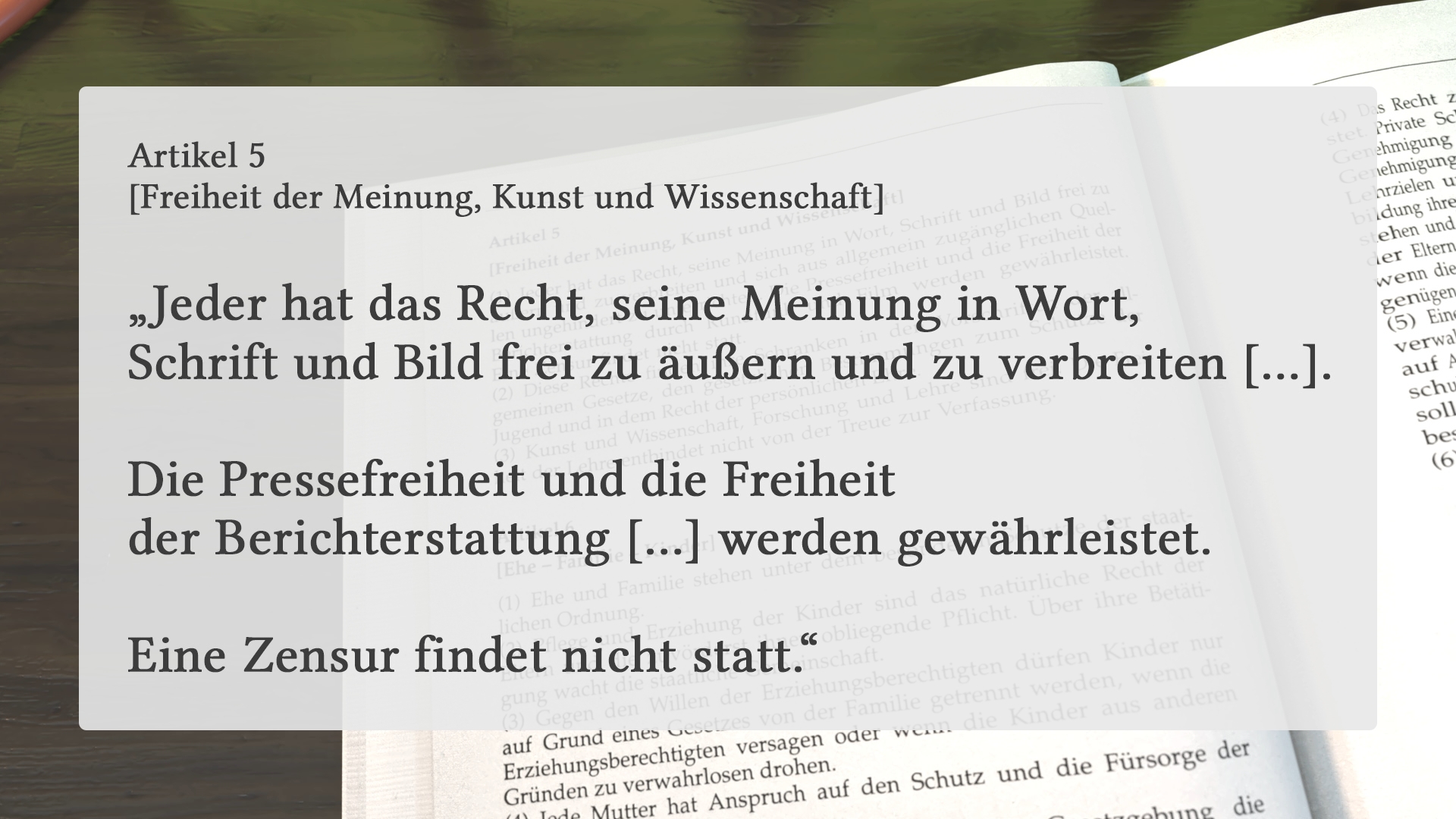 Geöffnete Buchseite mit Artikel 5 zur Freiheit der Meinung, Kunst und Wissenschaft, hervorgehobener Text zu Meinungsfreiheit und Pressefreiheit.