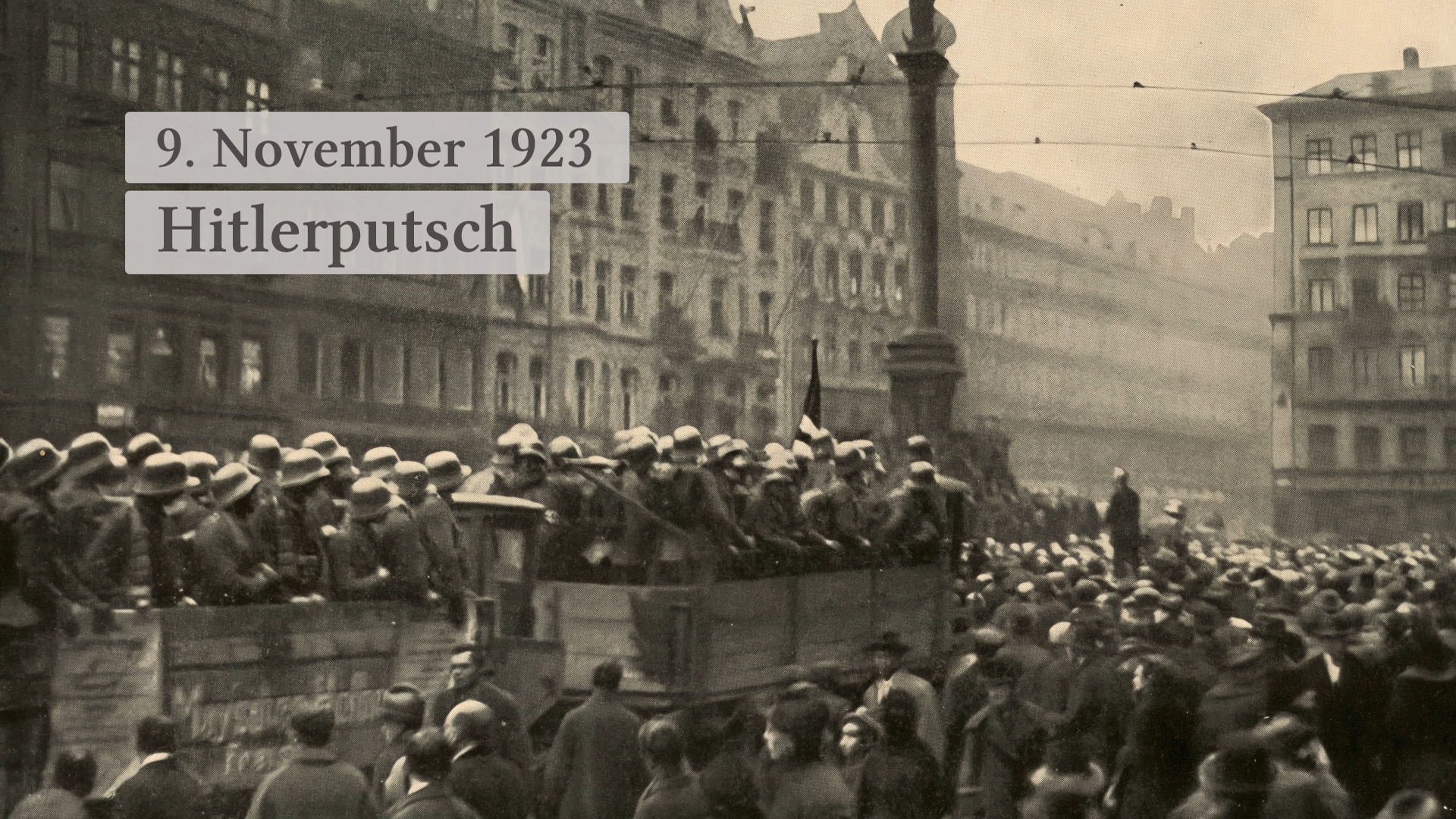 Historisches Foto vom Hitlerputsch am 9. November 1923, mit Menschenmengen und Soldaten auf einem Lastwagen.
