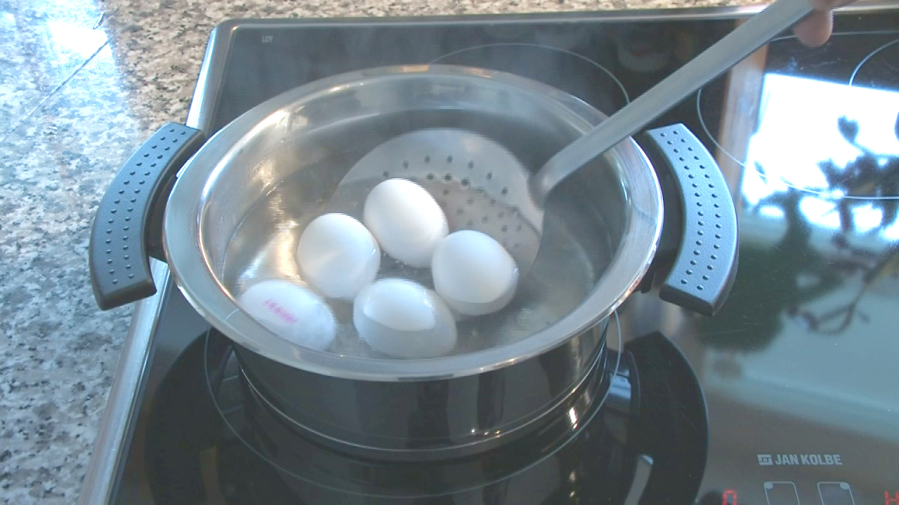 Fünf weiße Eier werden in einem Topf mit kochendem Wasser gekocht.