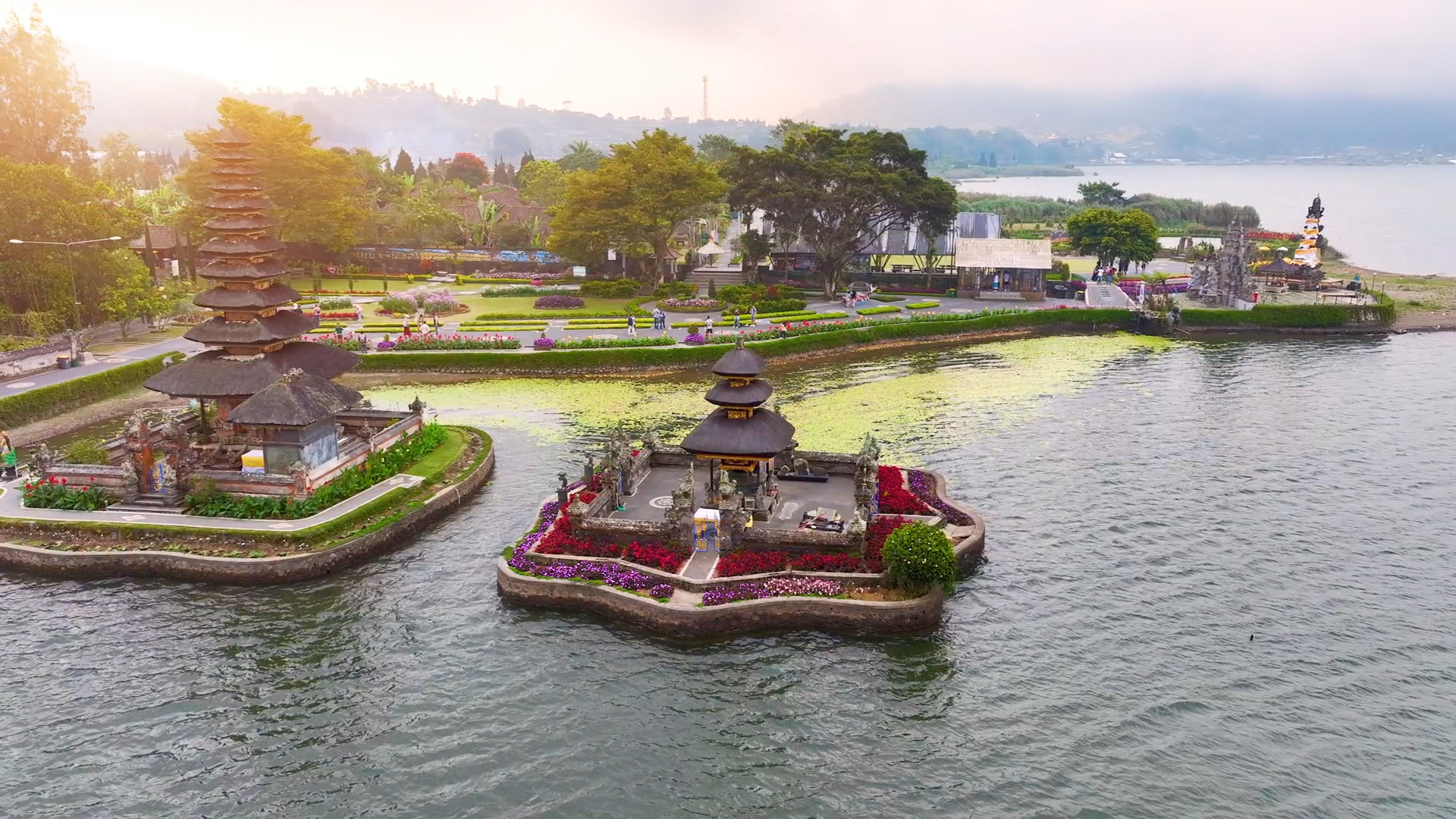 Luftaufnahme des Ulun Danu Bratan Tempels auf Bali, umgeben von Wasser und üppiger Vegetation.