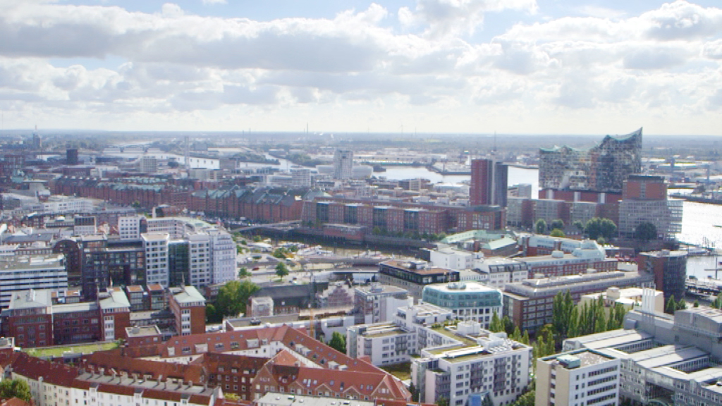 Blick auf die Hafenstadt mit modernen Gebäuden und Wasserflächen im Hintergrund.