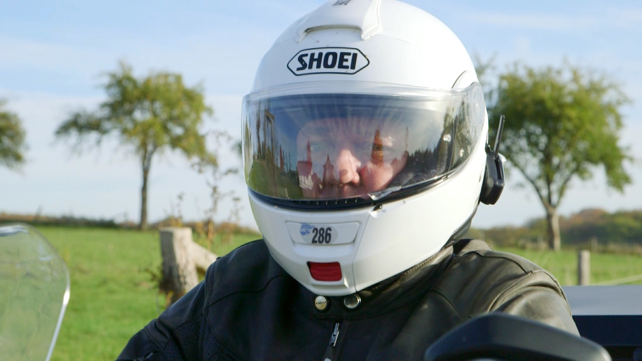 Motorradfahrer mit Shoei-Helm, Blick auf die Landschaft im Hintergrund.
