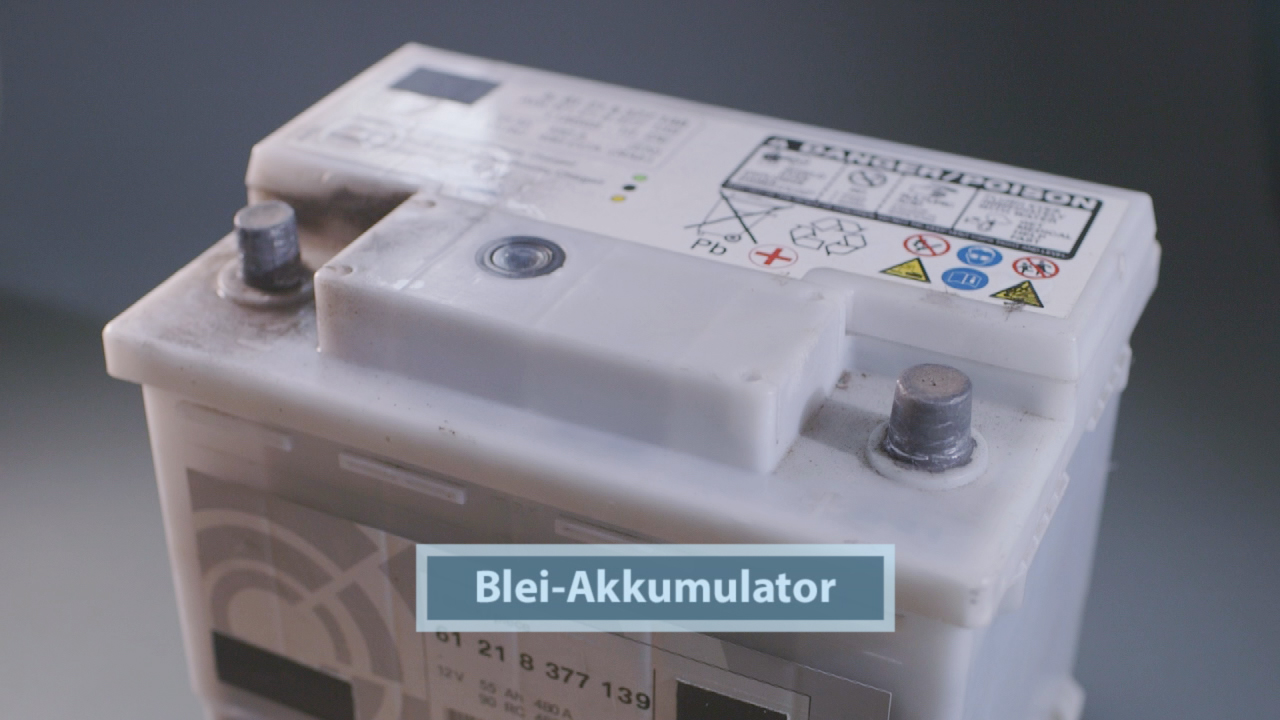 Blei-Akkumulator mit sichtbaren Anschlüssen und Warnsymbolen auf dem Etikett.