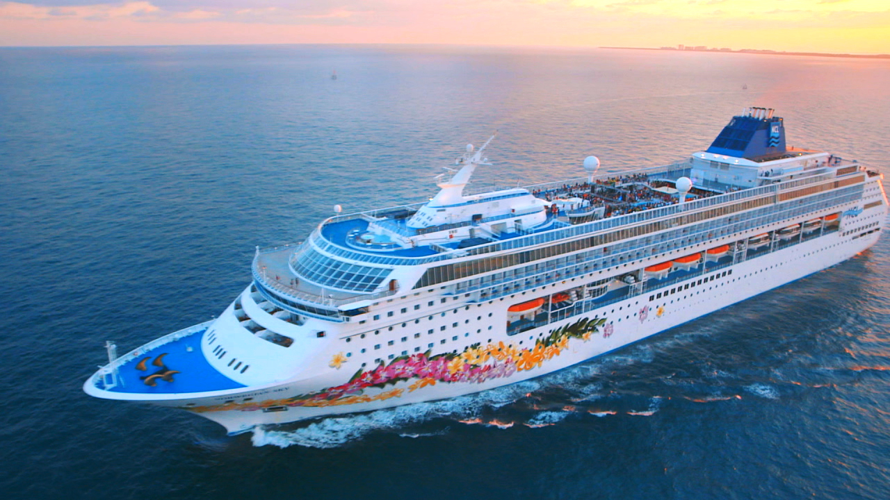 Kreuzfahrtschiff mit buntem Design fährt über das Meer bei Sonnenuntergang.