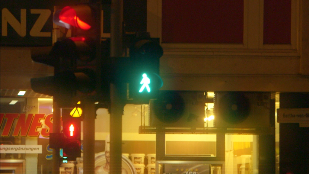 Grünes Ampelmännchen zeigt an, dass Fußgänger die Straße überqueren können.