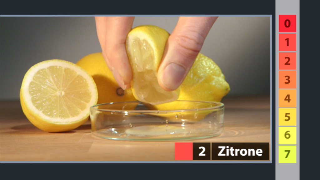 Eine Hand drückt eine Zitrone über einer kleinen Schale aus, während weitere Zitronen im Hintergrund liegen.
