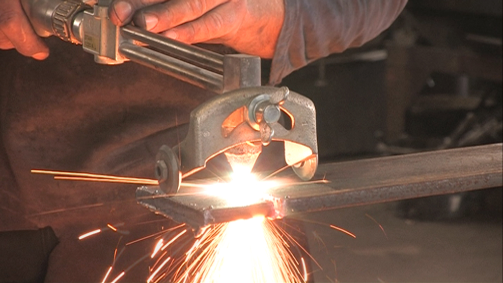 Ein Handwerker schneidet Metall mit einem Brennschneider, Funken sprühen.