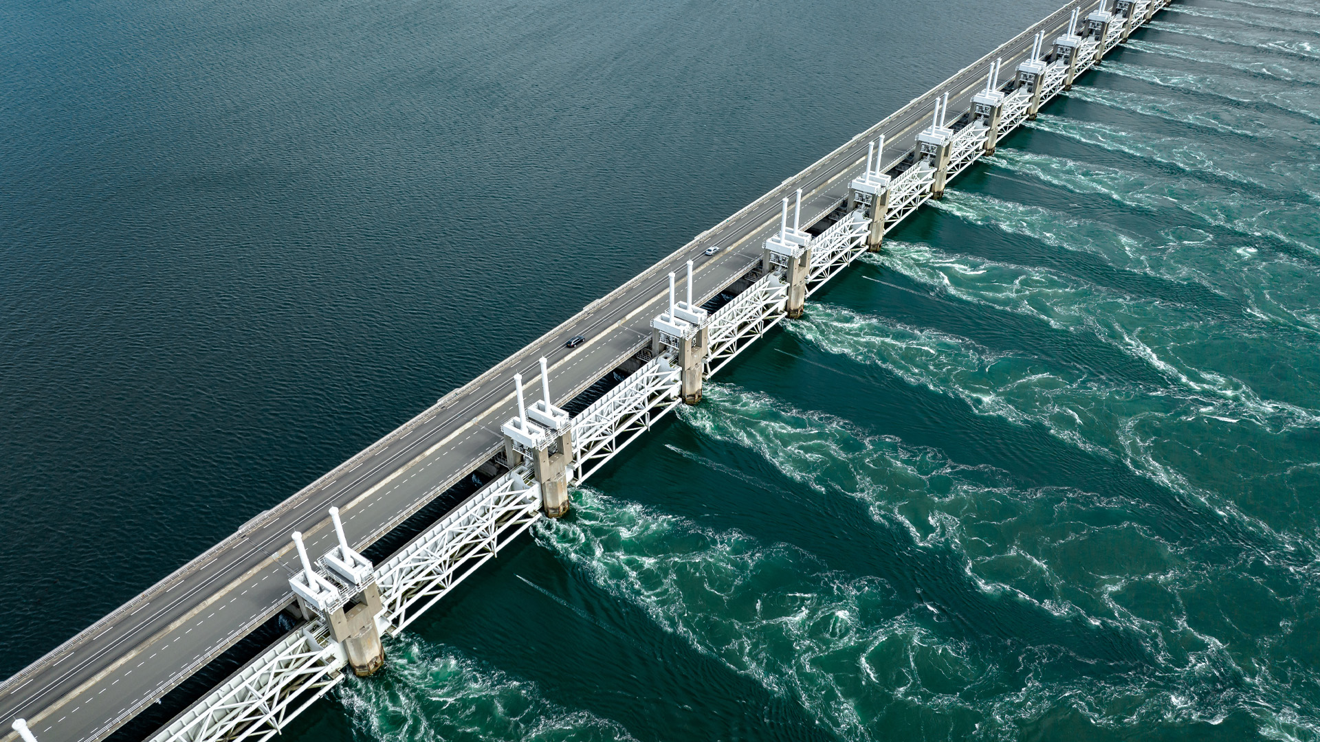 Luftaufnahme eines Staudamms mit Wasser, das durch die Schleusen fließt und Wirbel bildet
