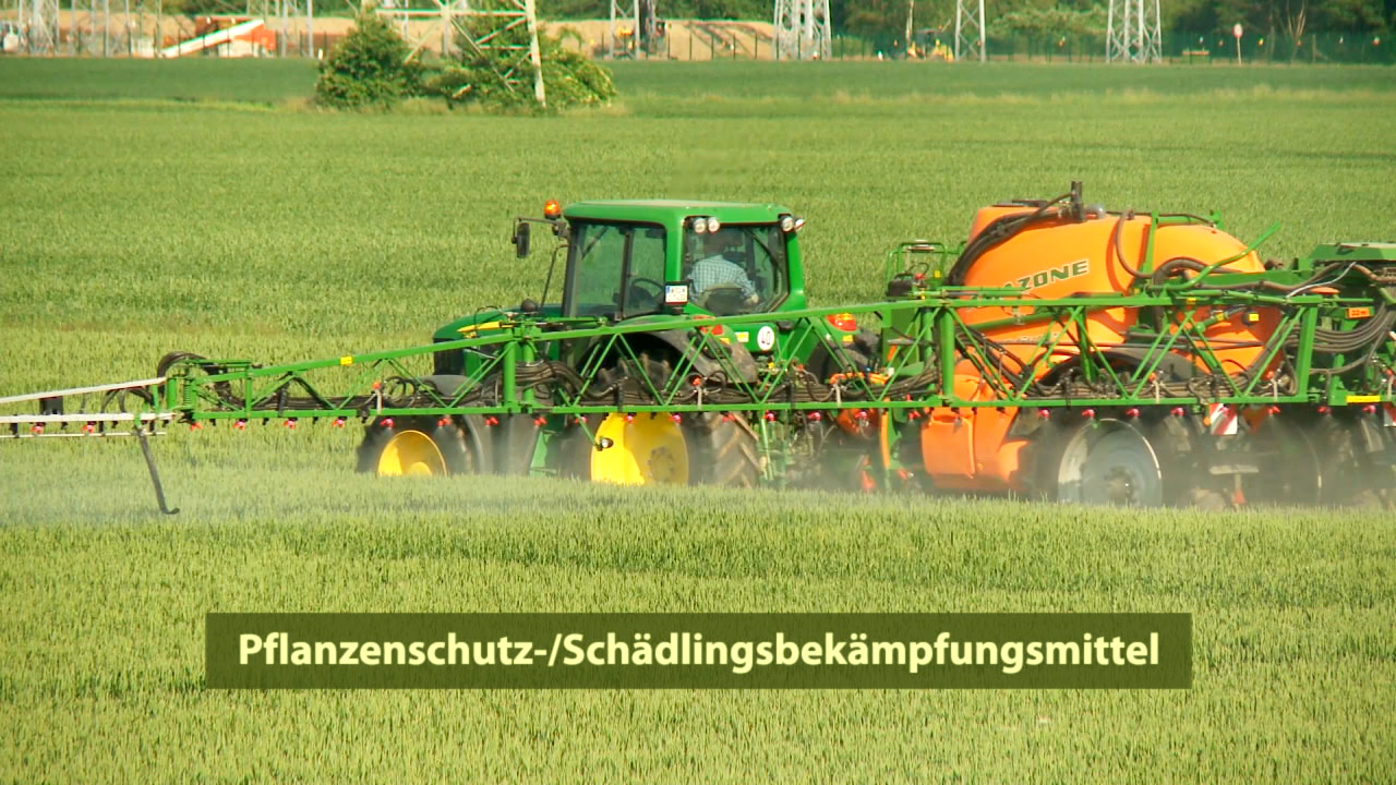 Ein Traktor sprüht Pflanzenschutzmittel auf ein Feld mit Getreide.