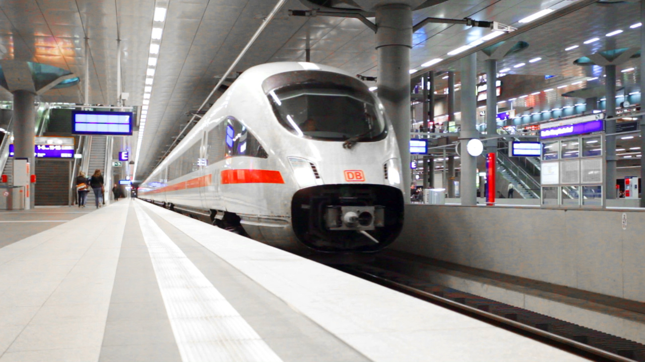 Ein ICE-Zug der Deutschen Bahn fährt in einen modernen Bahnhof ein.