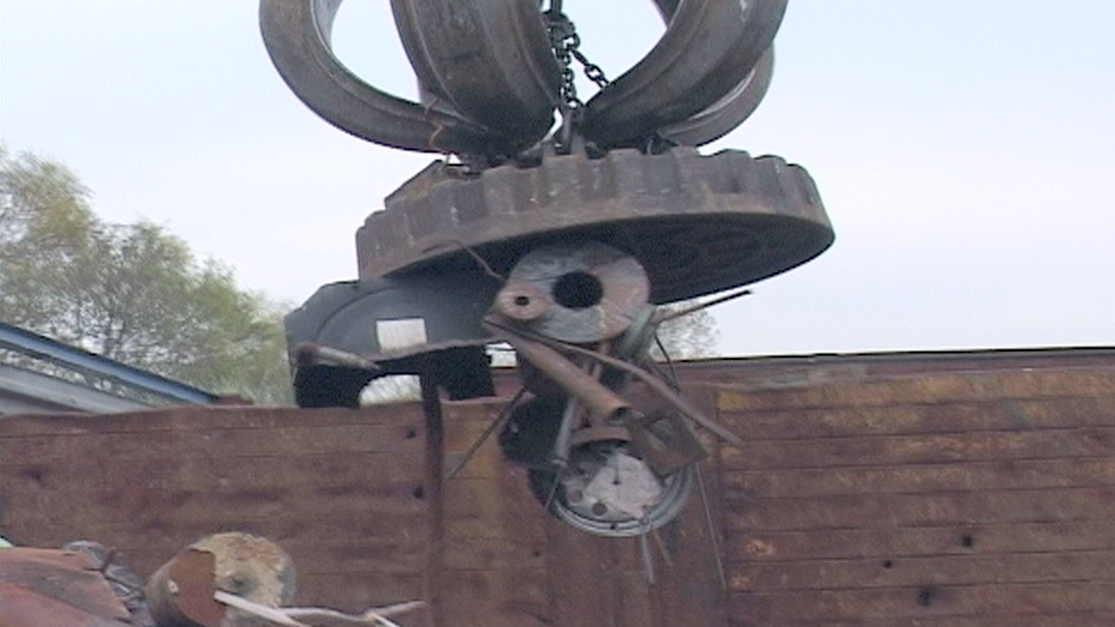 Ein Kran hebt Metallteile und Schrott von einem Recyclingplatz.