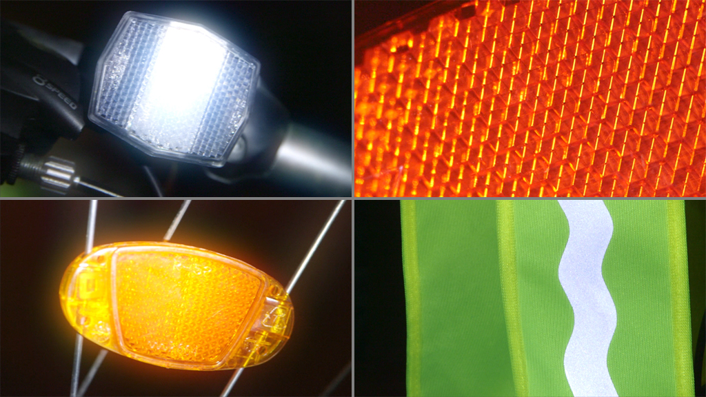 Nahaufnahme von Fahrradlichtern und Reflektoren in orange und weiß.