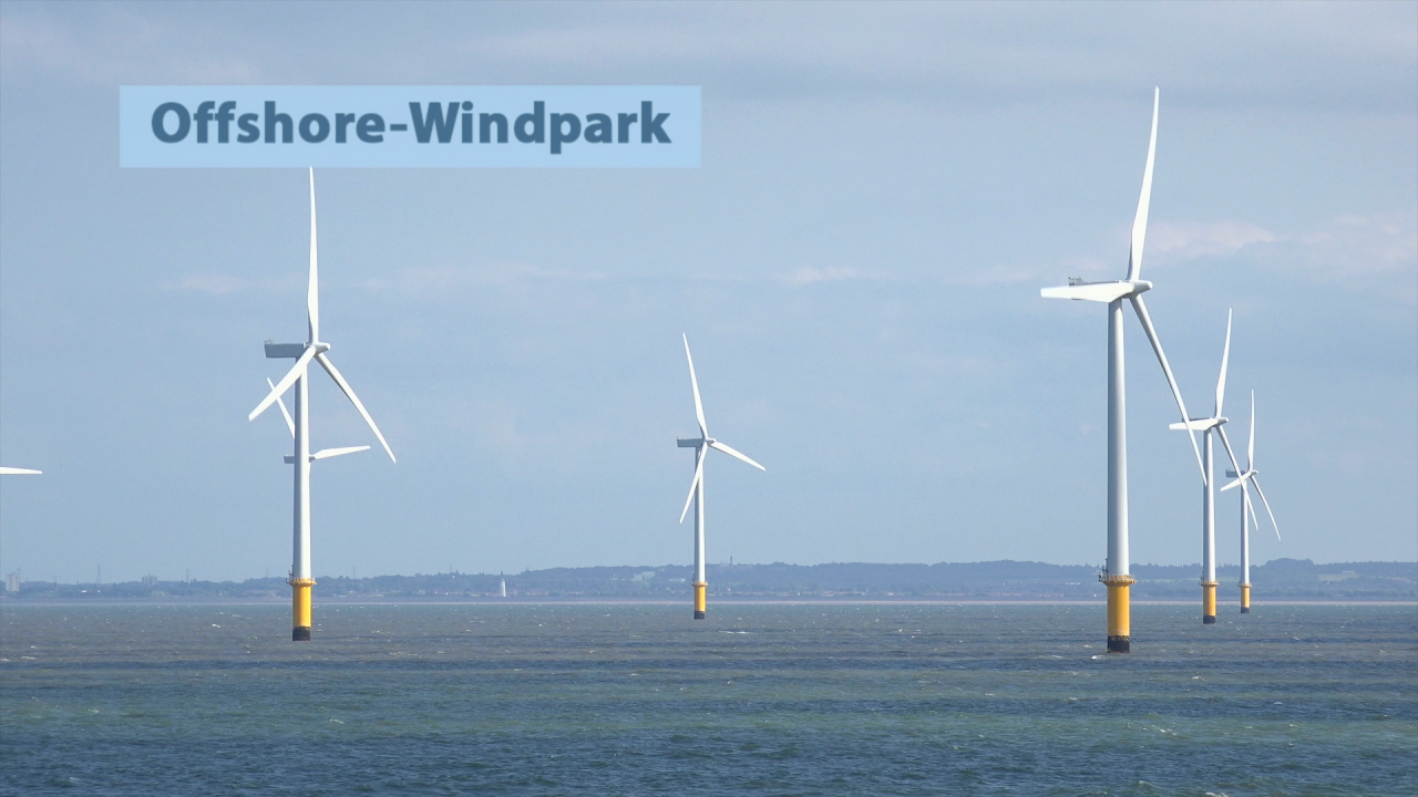 Offshore-Windpark mit mehreren Windturbinen im Meer, gelbe Fundamente, blauer Himmel.