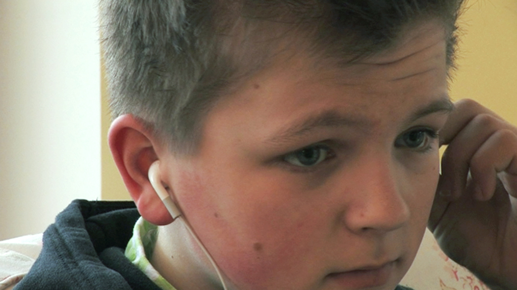 Ein Junge mit kurzen, braunen Haaren hört aufmerksam Musik über Kopfhörer.