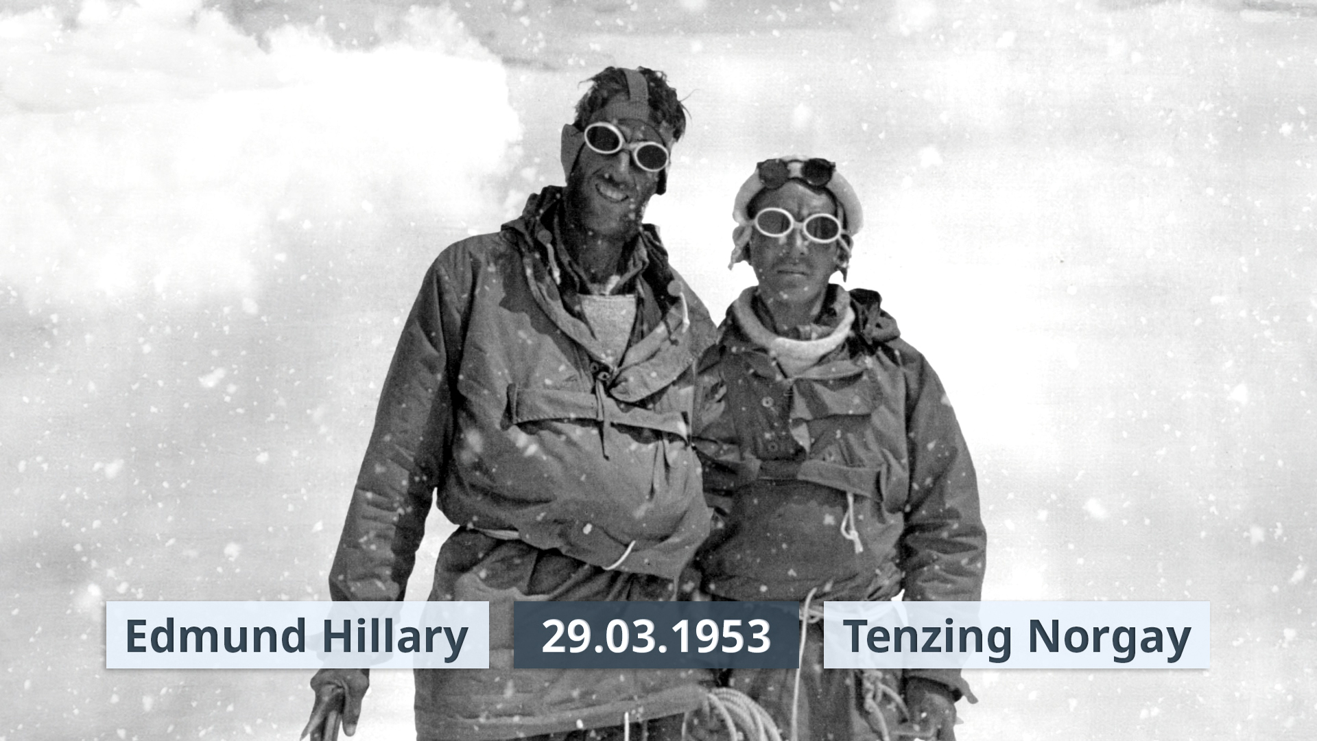 Edmund Hillary und Tenzing Norgay stehen in Schneefall zusammen, datiert auf den 29.03.1953.