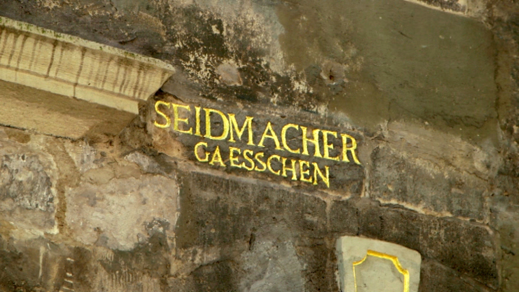 Der Schriftzug 'Seidmacher Gaesschen' in goldener Schrift an einer steinernen Wand.
