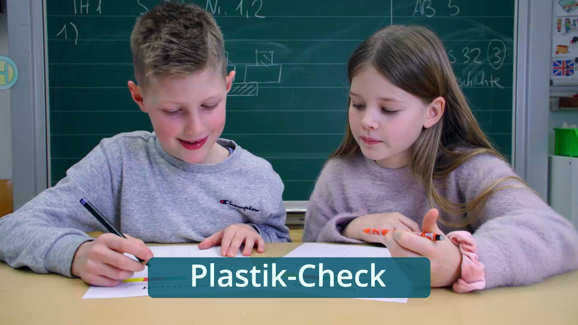 Zwei Kinder sitzen an einem Tisch vor einer Tafel und schreiben auf Papier, darunter der Schriftzug 'Plastik-Check'